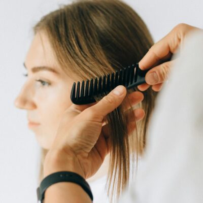 Close-up of a woman receiving hair care and combing at a salon.