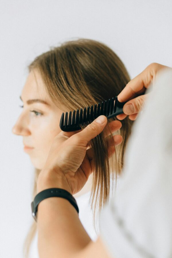 Close-up of a woman receiving hair care and combing at a salon.