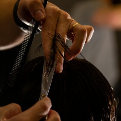 Detailed shot of a barber cutting hair with scissors and comb, focusing on precision.