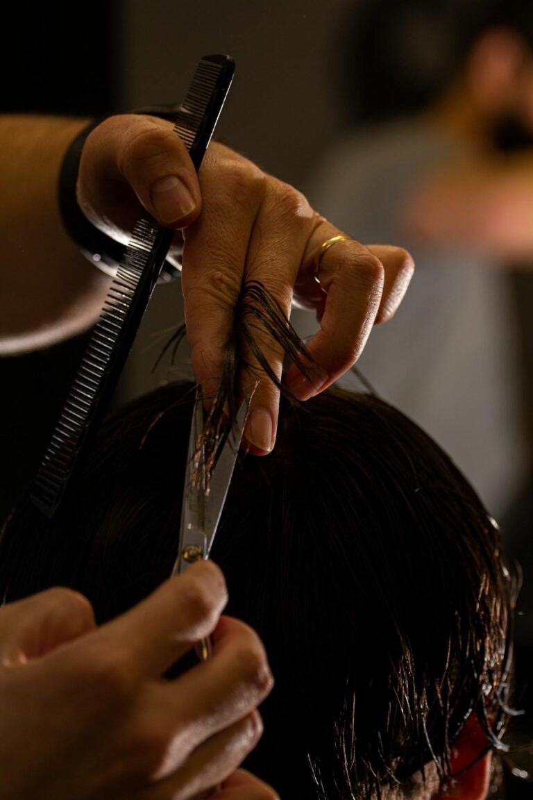 Detailed shot of a barber cutting hair with scissors and comb, focusing on precision.