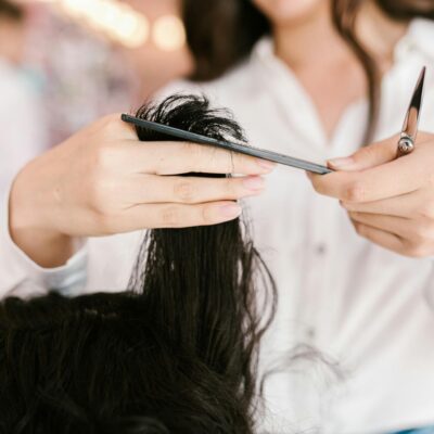 Professional hairdresser cutting hair with scissors and comb in a salon setting.