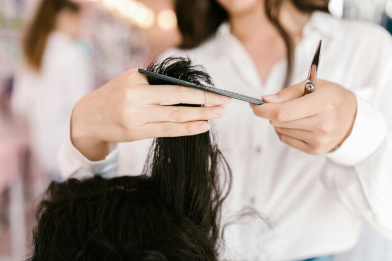 Professional hairdresser cutting hair with scissors and comb in a salon setting.