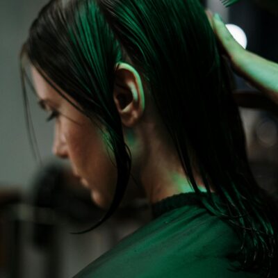 Side view of a woman getting a haircut with wet hair in a salon setting.