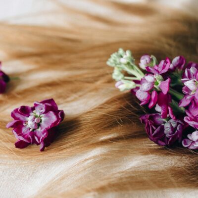 Vivid purple flowers beautifully arranged on a luxurious spread of blonde hair, symbolizing natural elegance.