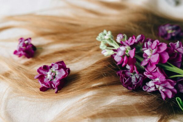 Vivid purple flowers beautifully arranged on a luxurious spread of blonde hair, symbolizing natural elegance.